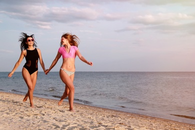 Photo of Young woman in bikini with girlfriend on beach. Lovely couple