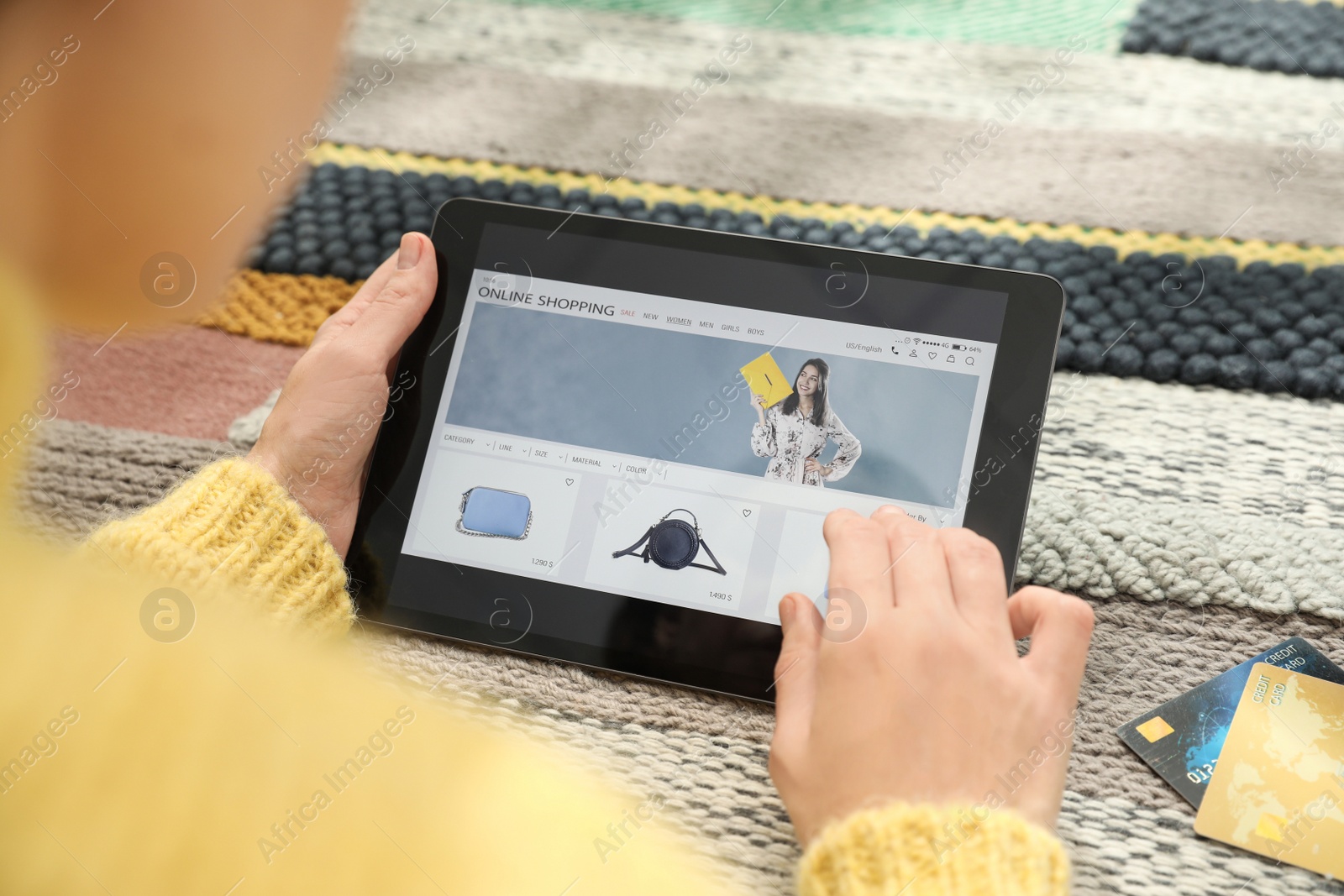 Photo of Woman with credit cards using tablet for online shopping on carpet, closeup