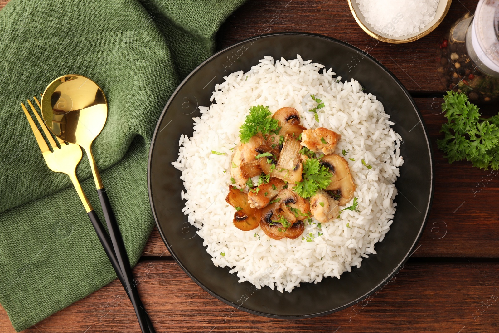 Photo of Delicious rice with mushrooms and parsley served on wooden table, flat lay