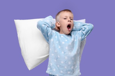 Photo of Sleepy boy with pillow yawning on purple background. Insomnia problem