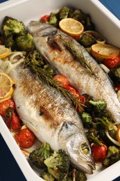 Photo of Delicious fish with vegetables and lemon in baking dish on table, closeup