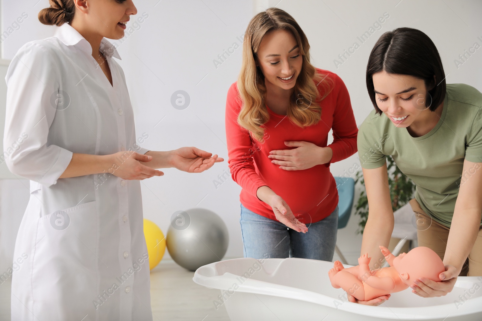 Photo of Pregnant women learning how to bathe baby at courses for expectant mothers indoors