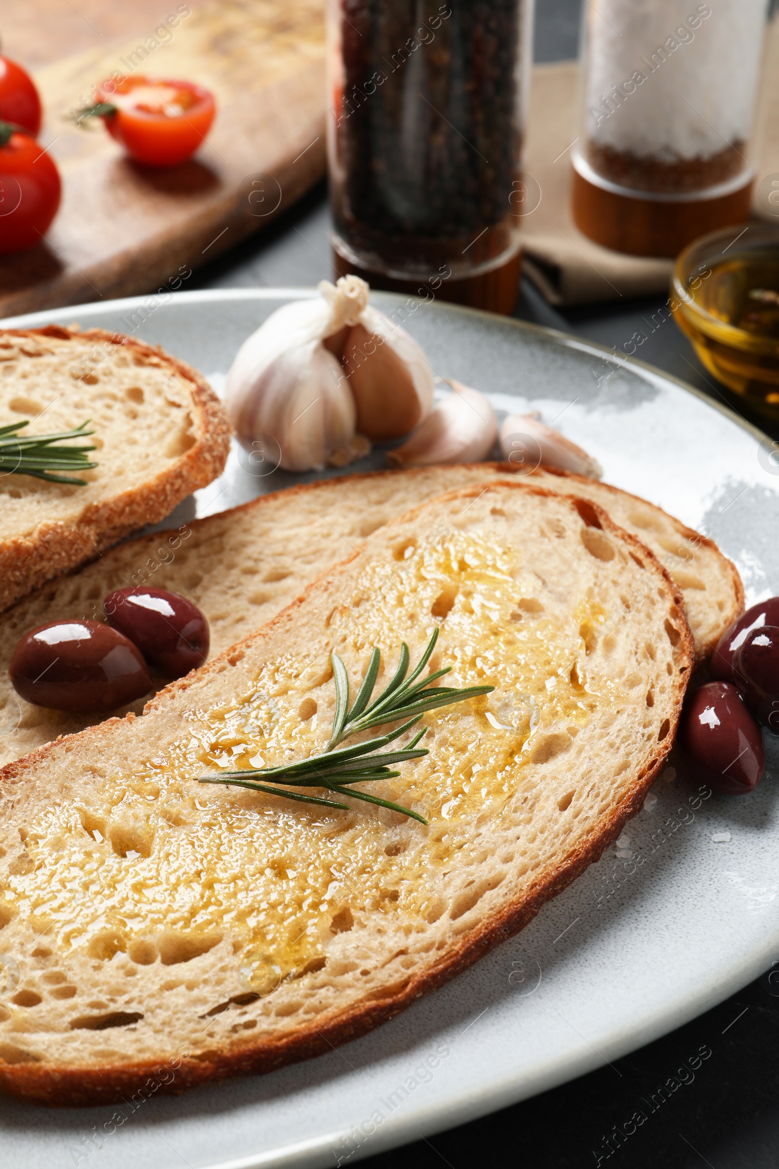 Photo of Tasty bruschettas with oil and rosemary on plate, closeup