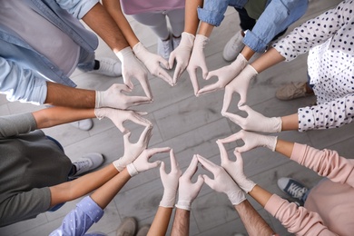 Photo of People in white medical gloves showing hearts with fingers indoors, top view