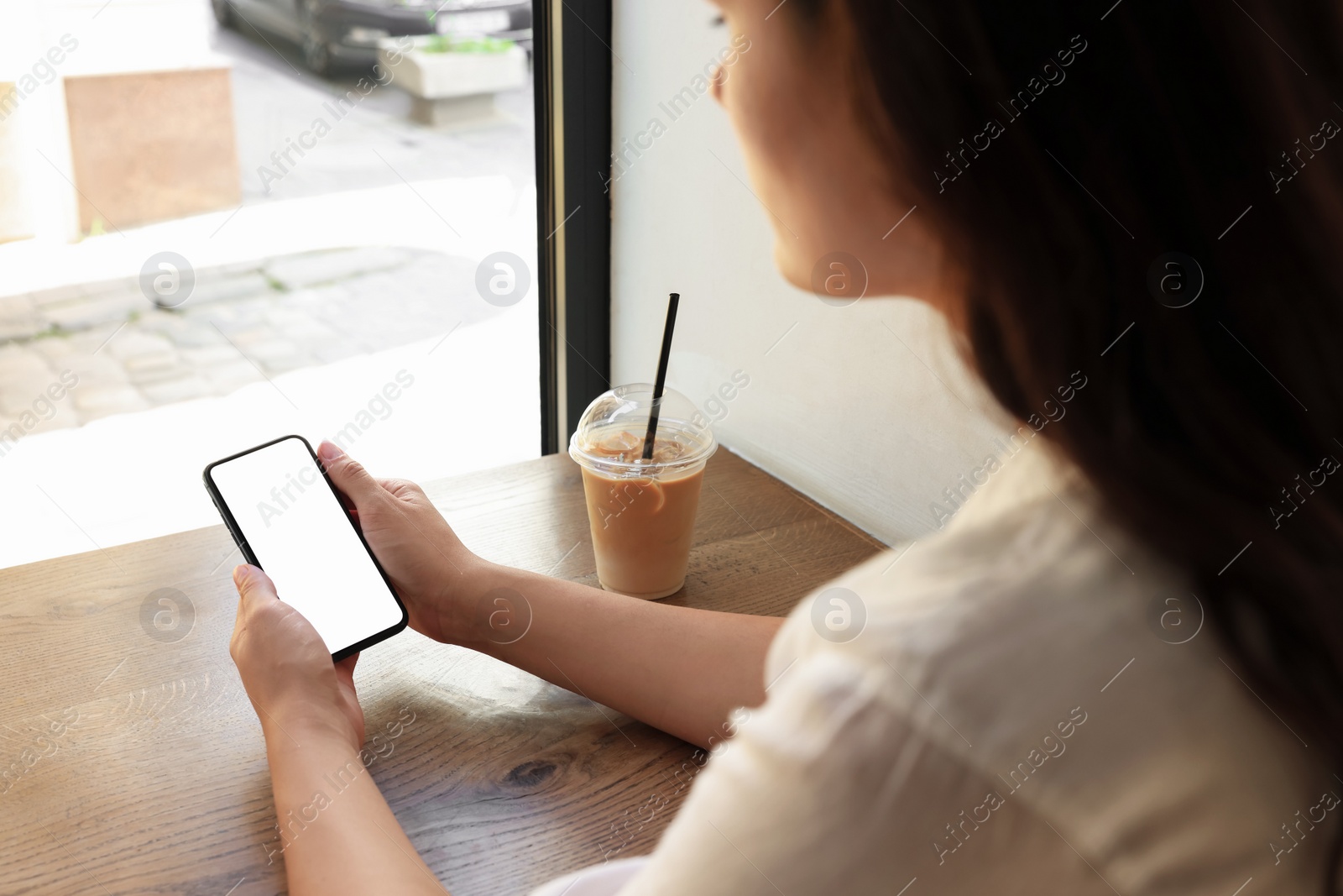 Photo of Woman using smartphone near window in cafe, closeup