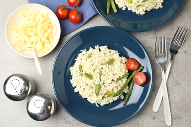 Photo of Delicious risotto with asparagus on grey table, flat lay