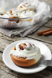 Photo of Tasty cinnamon roll with cream on wooden table. Space for text