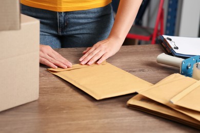 Photo of Post office worker sealing adhesive paper bag at counter indoors, closeup