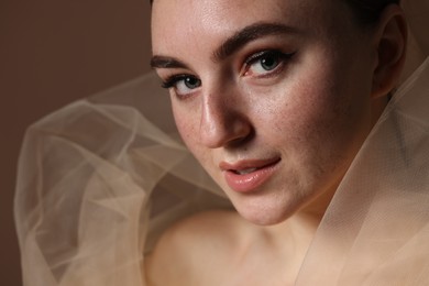 Fashionable portrait of beautiful woman with fake freckles on brown background, closeup