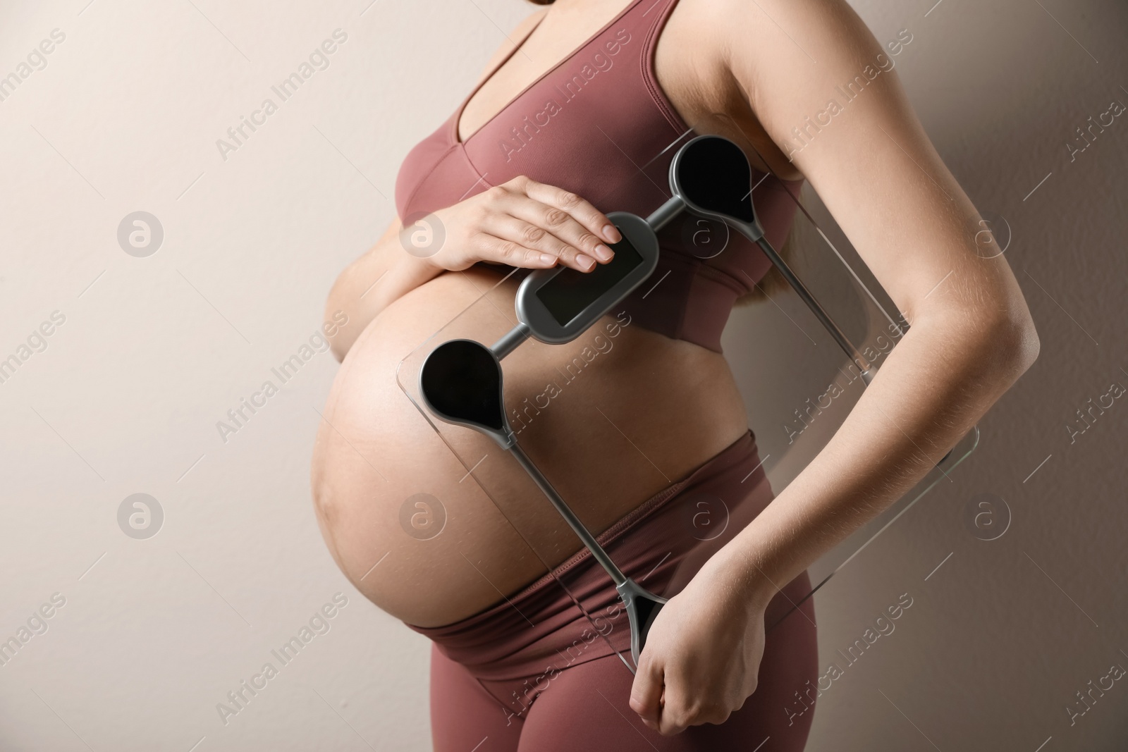 Photo of Pregnant woman with scales on beige background, closeup