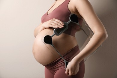 Pregnant woman with scales on beige background, closeup