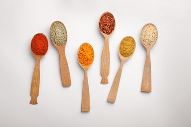 Composition with different aromatic spices in wooden spoons on white background