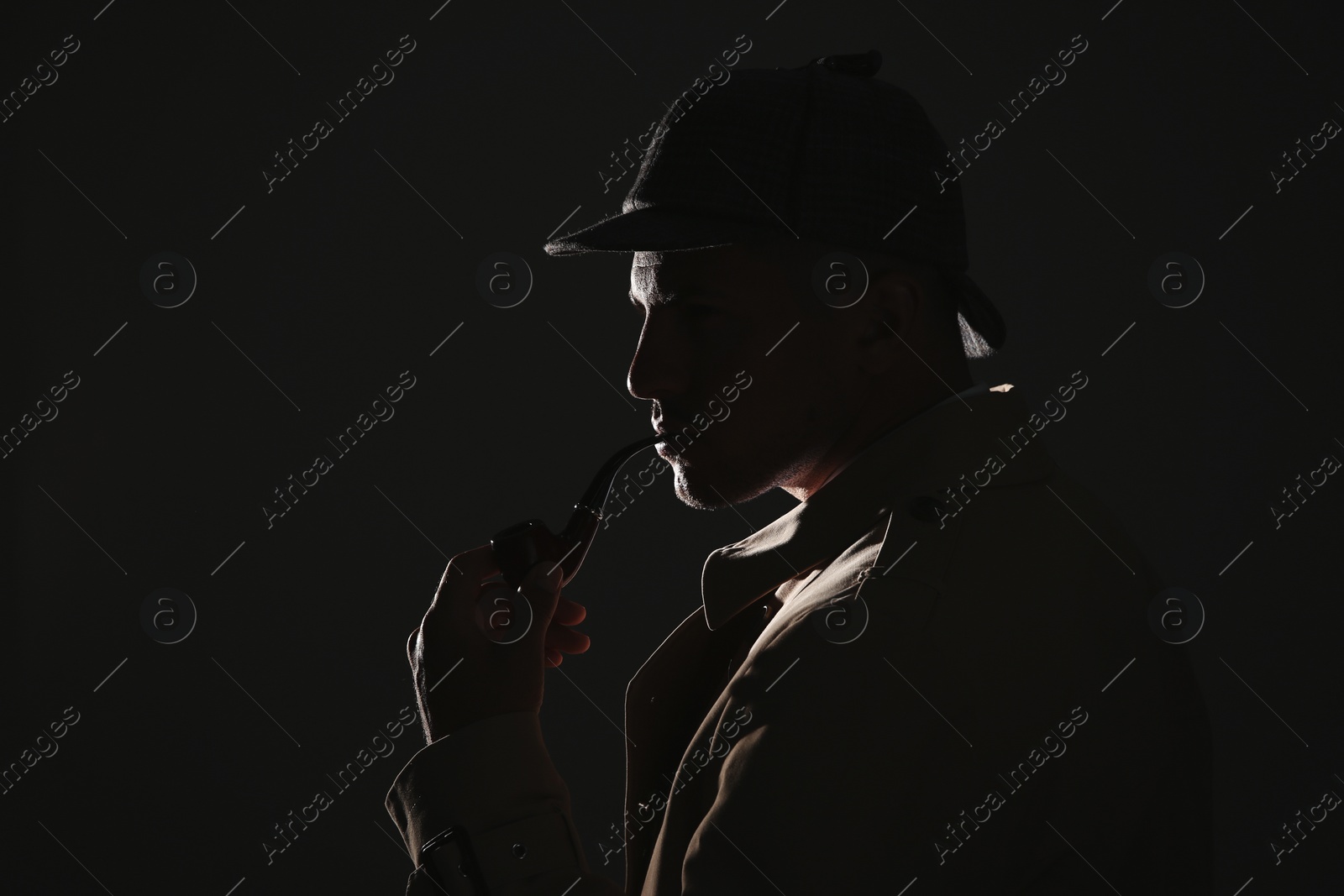 Photo of Old fashioned detective with smoking pipe on dark background