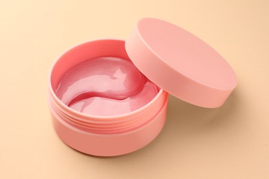 Photo of Jar of under eye patches on beige background, closeup. Cosmetic product