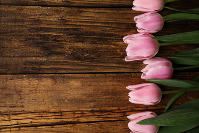 Photo of Beautiful pink spring tulips on wooden background, flat lay. Space for text