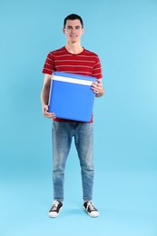 Man with cool box on light blue background