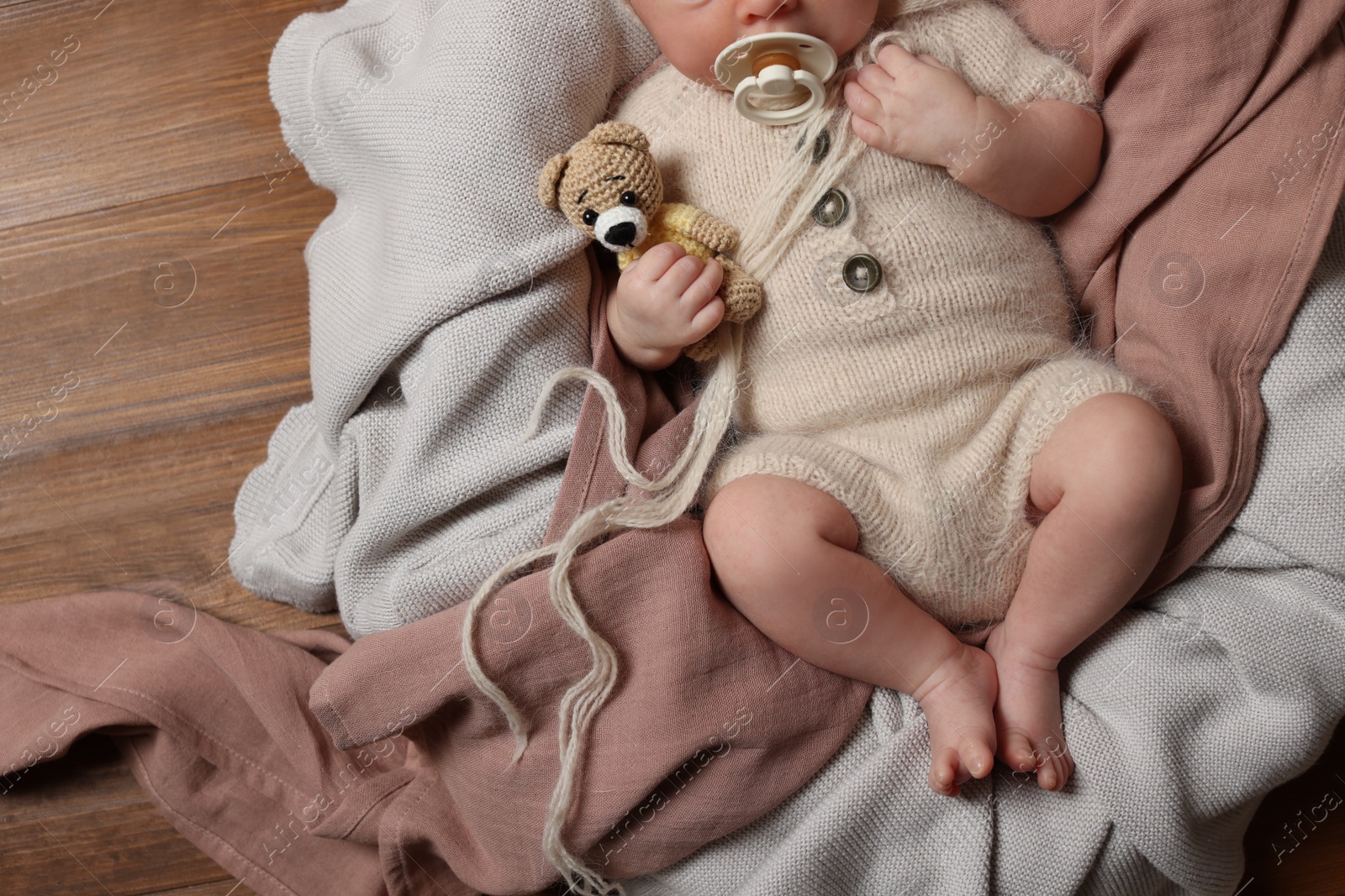 Photo of Top view of cute newborn baby with pacifier and toy bear on wooden background, closeup