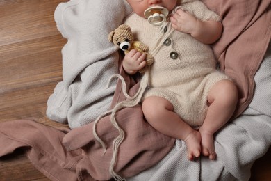 Photo of Top view of cute newborn baby with pacifier and toy bear on wooden background, closeup