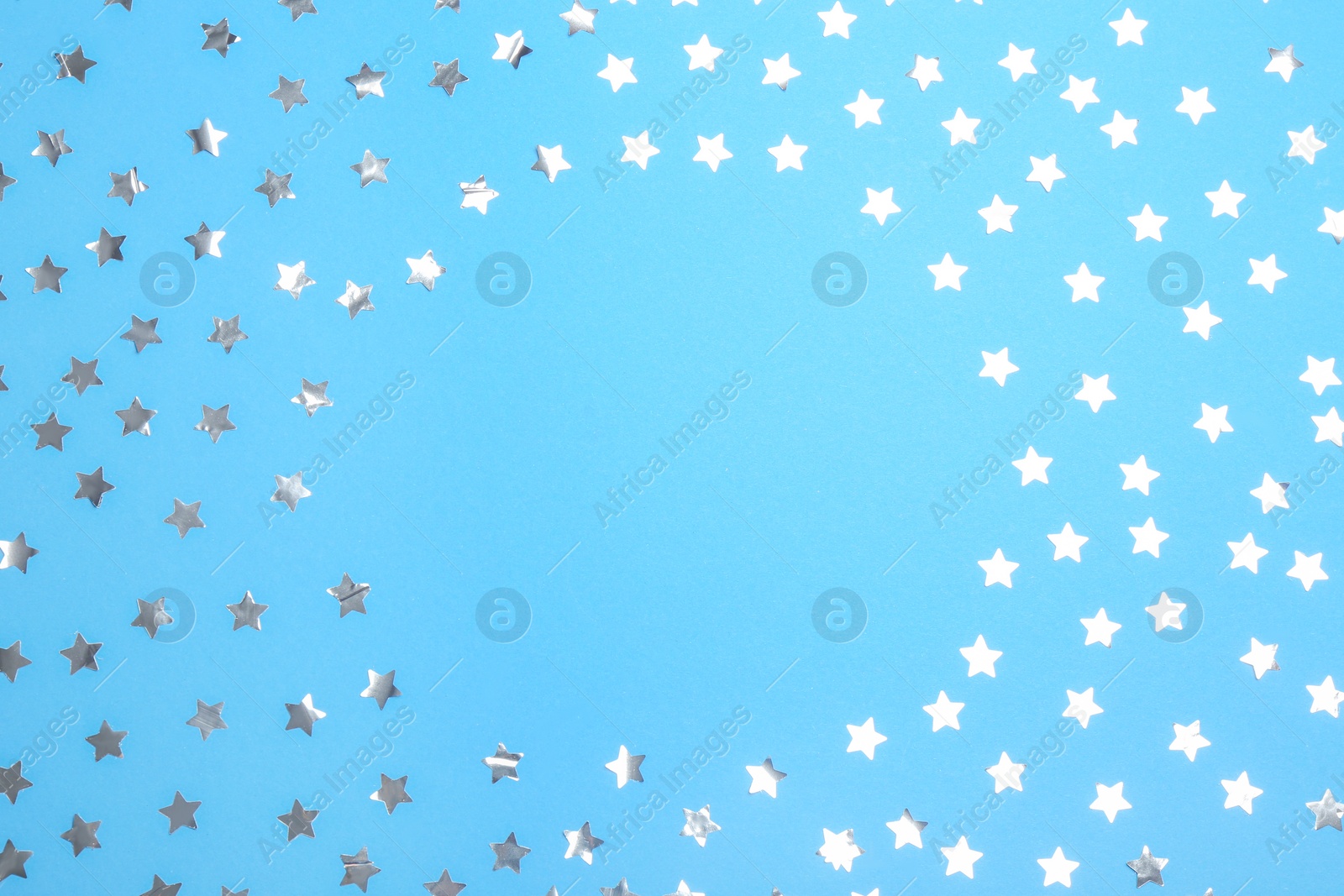 Photo of Frame of confetti stars with space for text on blue background, top view. Christmas celebration