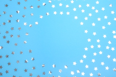 Photo of Frame of confetti stars with space for text on blue background, top view. Christmas celebration