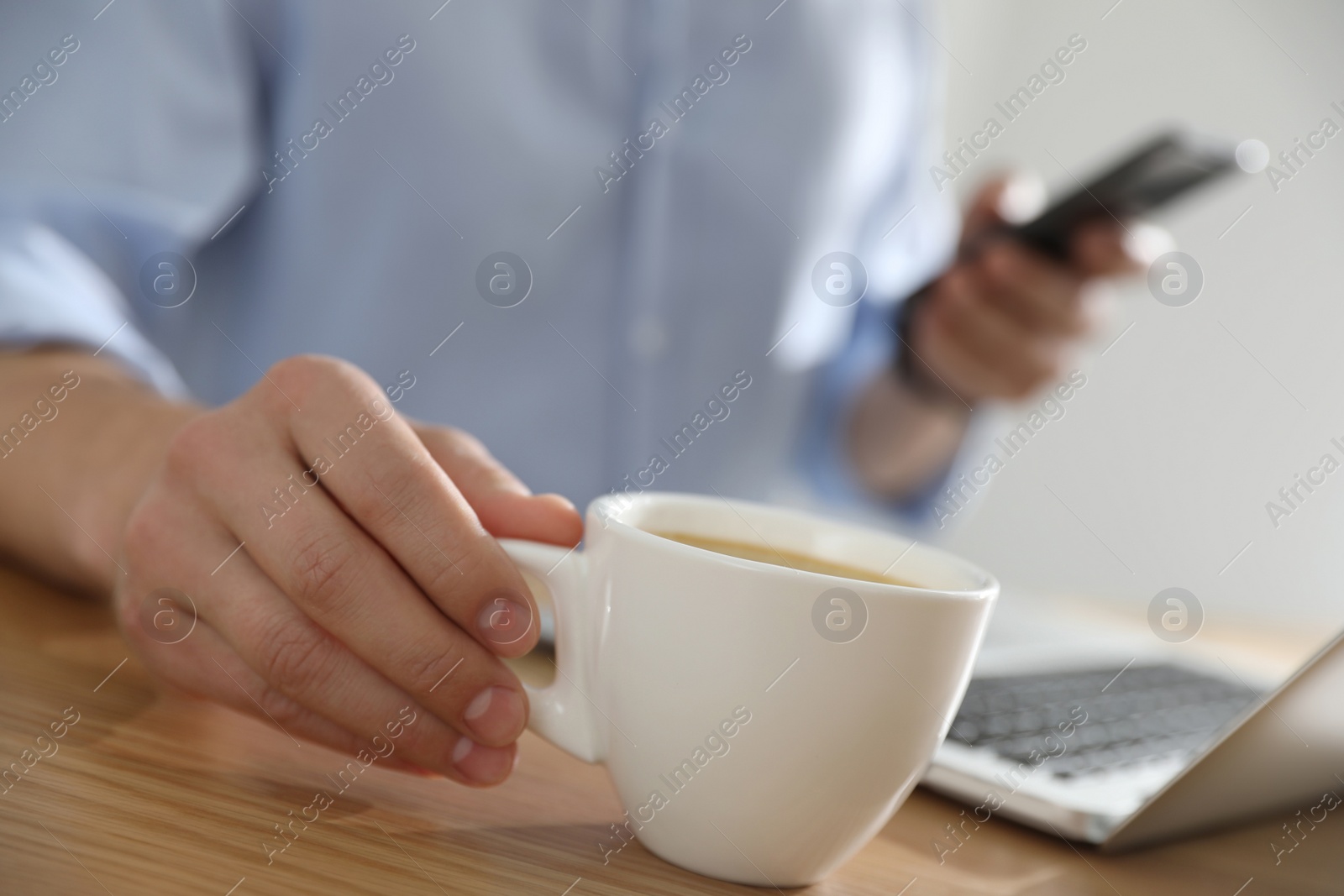 Photo of Man with cup of coffee at table indoors, closeup