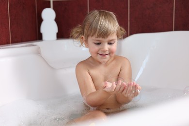 Happy girl having fun in bathtub at home