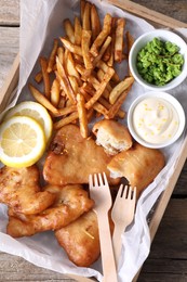 Tasty fish, chips, sauce and peas on wooden table, top view