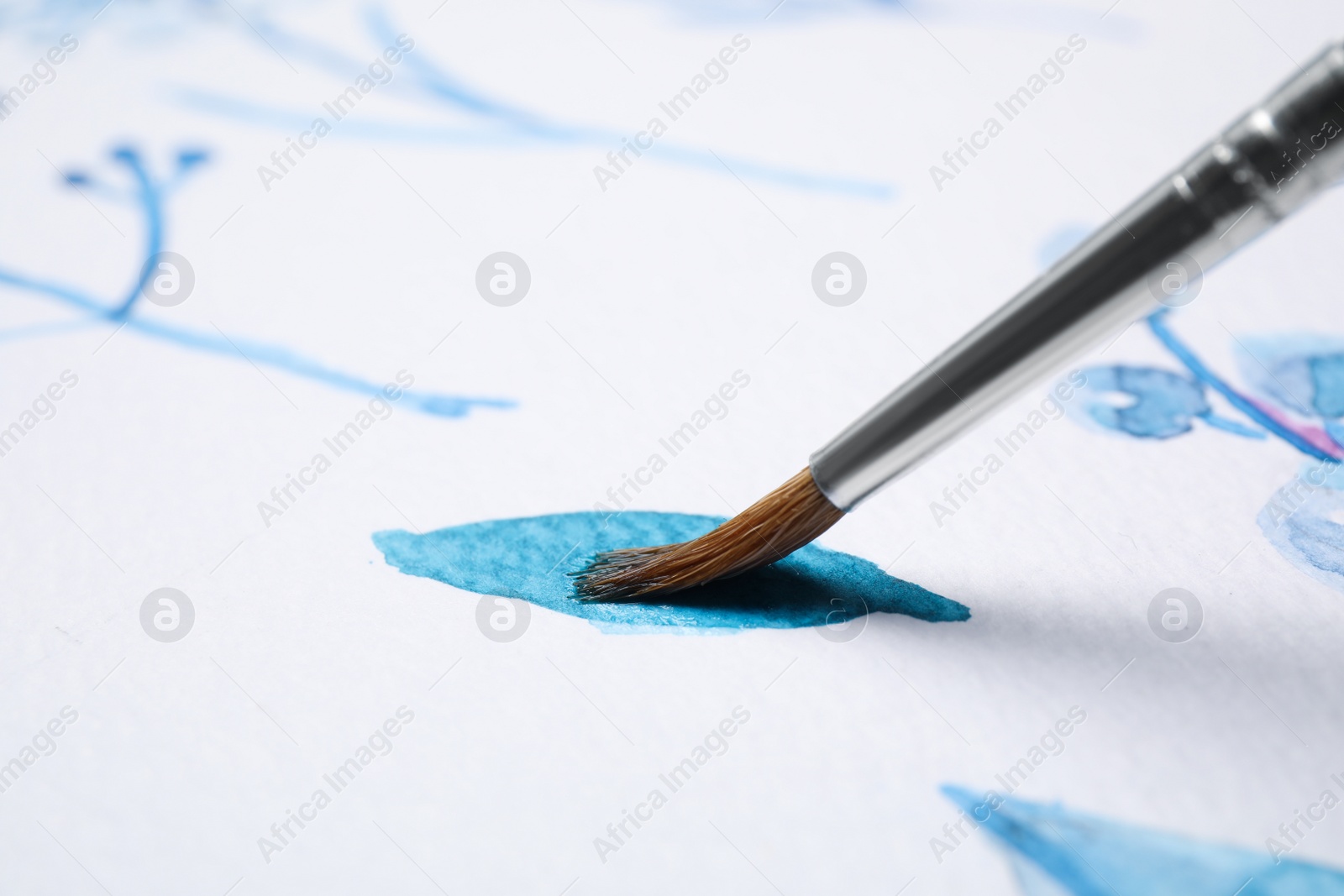 Photo of Painting leaf with blue watercolor on white paper, closeup