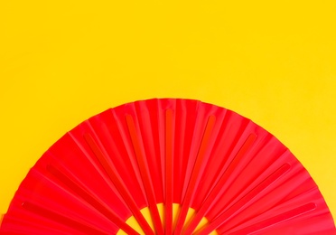 Photo of Red hand fan on yellow background, top view