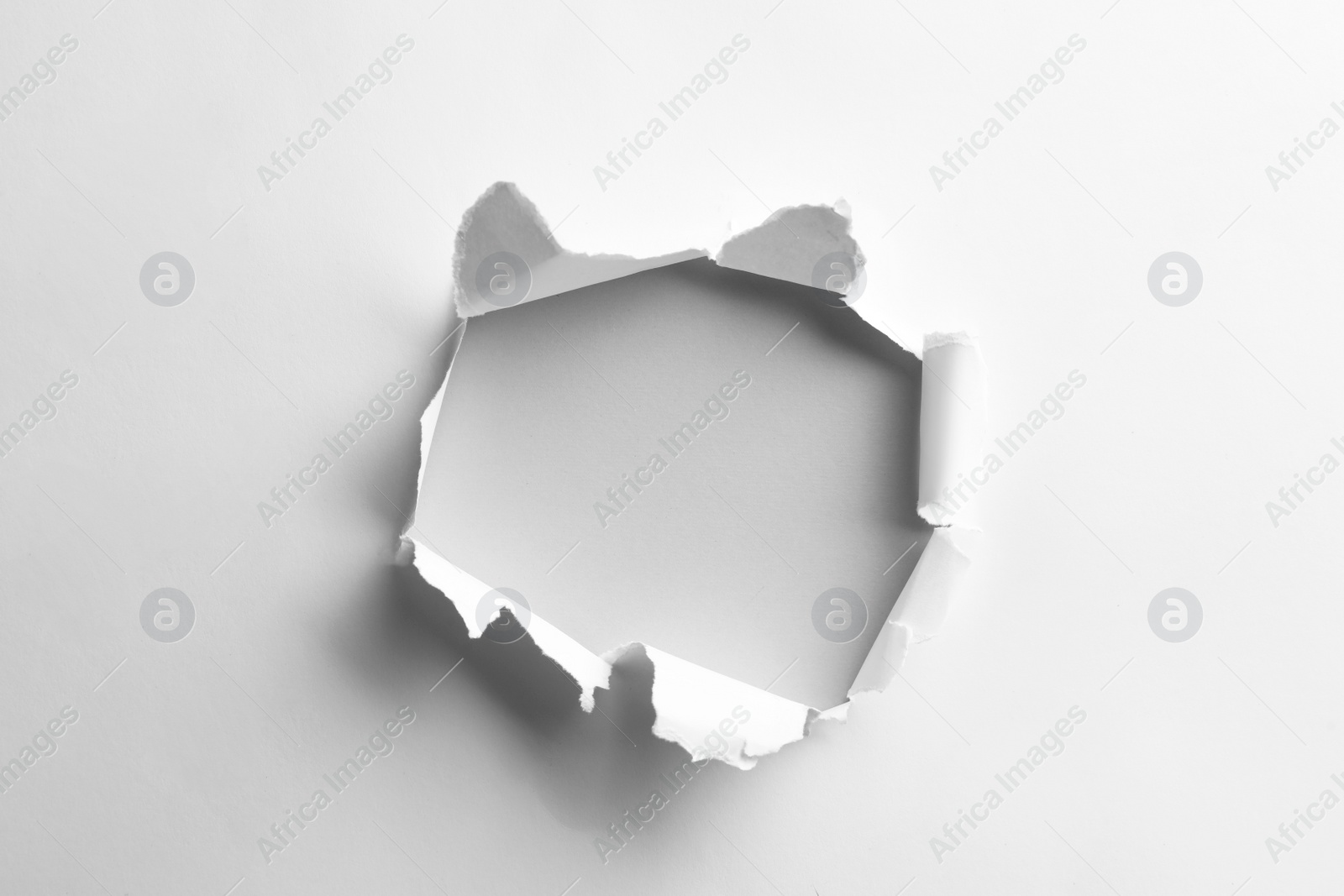 Photo of Hole in white paper on light background