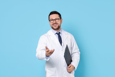 Photo of Smiling doctor with clipboard on light blue background