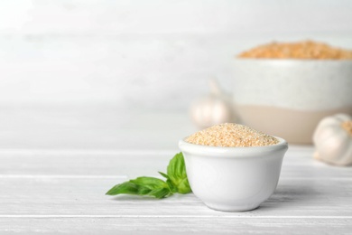 Bowl with granulated dried garlic on wooden table