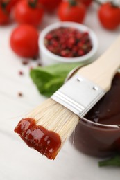 Photo of Marinade and basting brush on white table, closeup