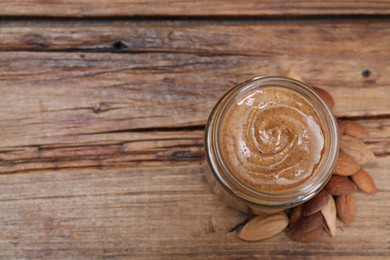 Tasty almond nut paste in jar on wooden table, top view. Space for text