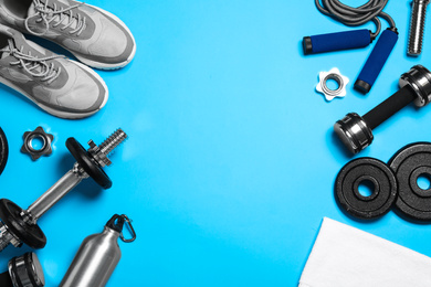 Photo of Gym equipment on light blue background, flat lay. Space for text