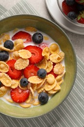 Photo of Corn flakes with berries in bowl served on grey table, flat lay