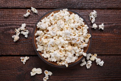 Photo of Bowl of tasty popcorn on wooden table, flat lay