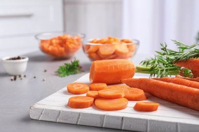 Photo of Board with slices of carrot on table