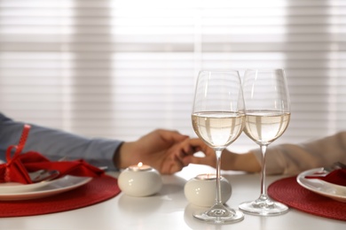 Photo of Couple having romantic dinner at home, focus on glasses of wine