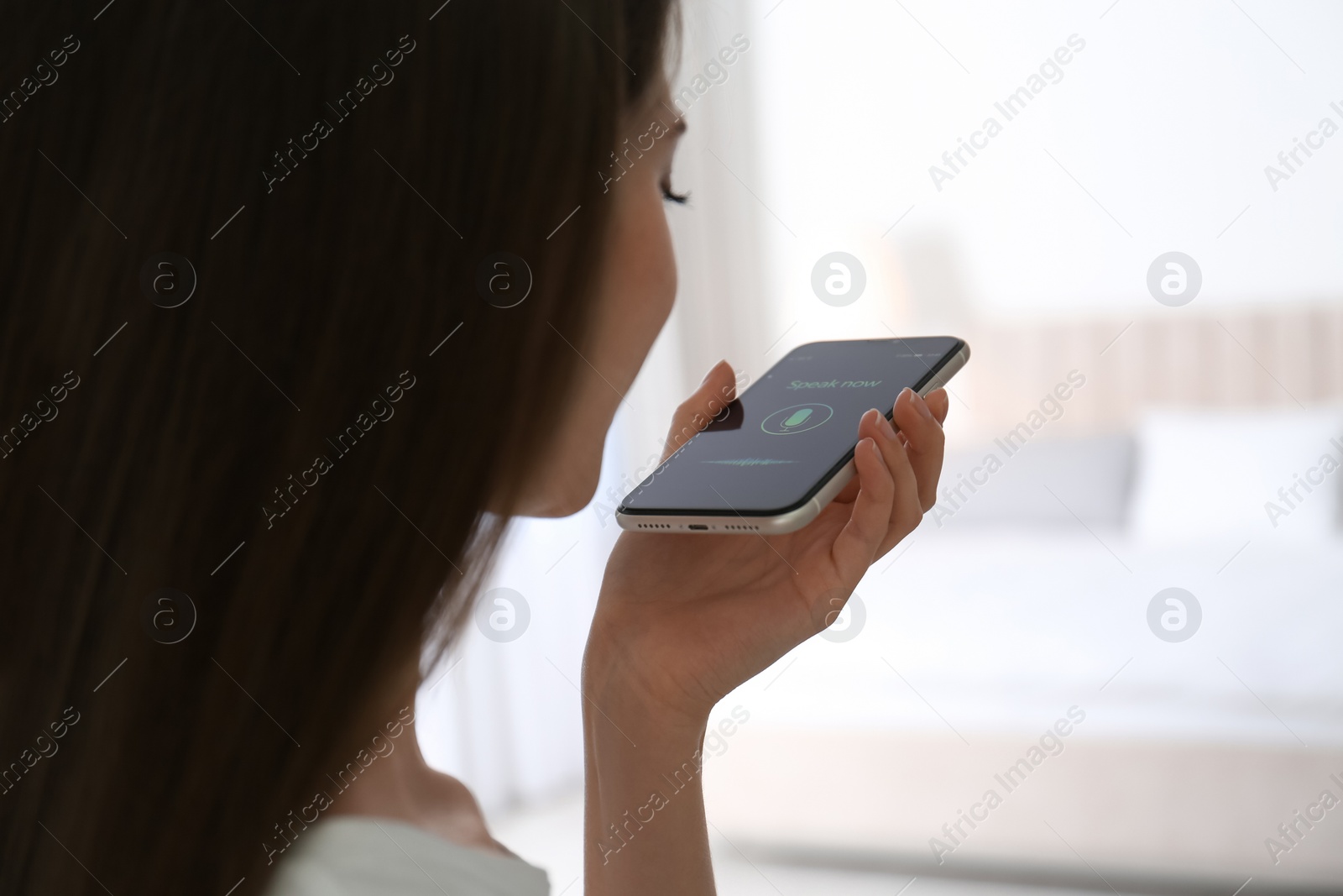 Photo of Woman using voice search on smartphone indoors, closeup