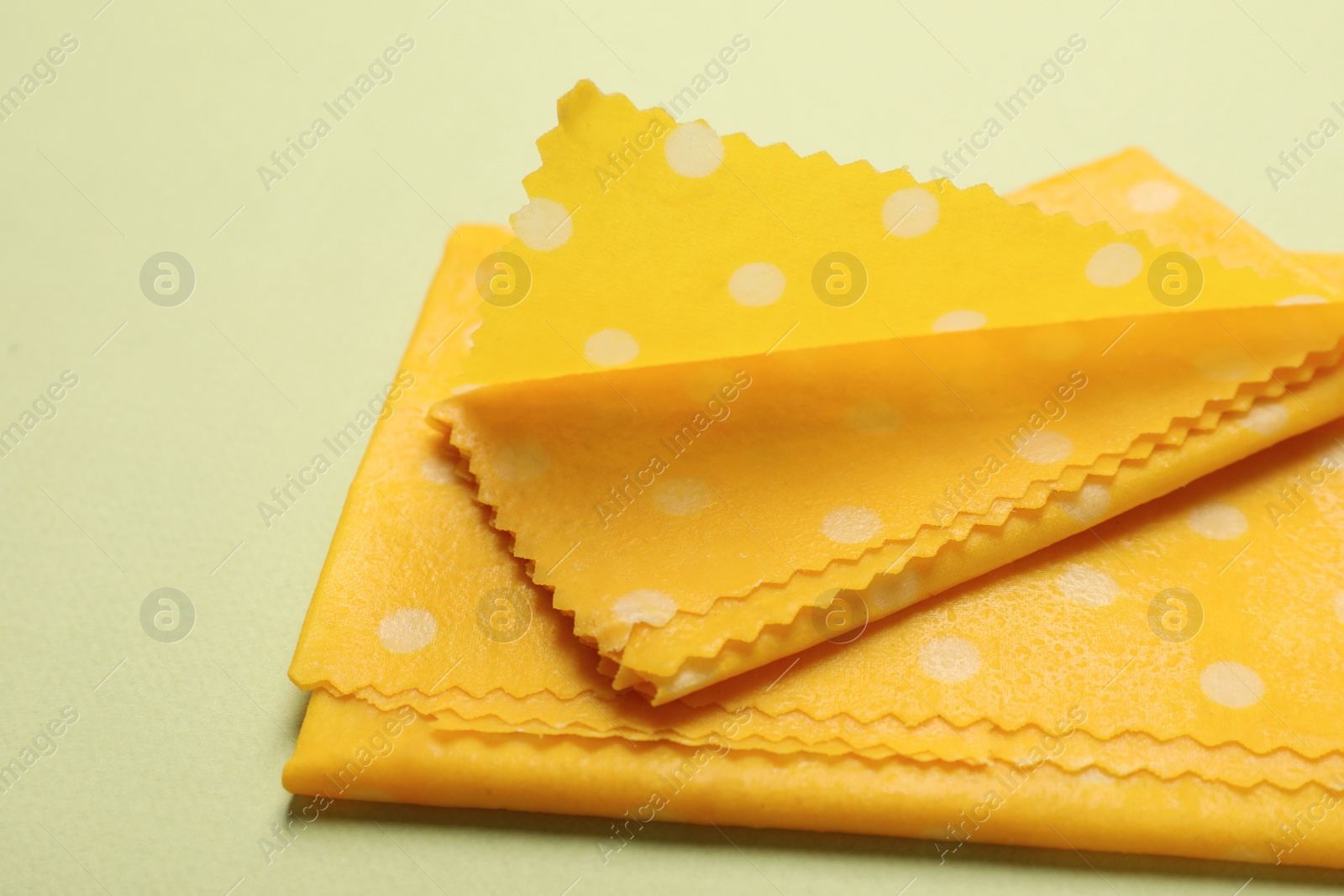 Photo of Beeswax food wraps on light green background, closeup