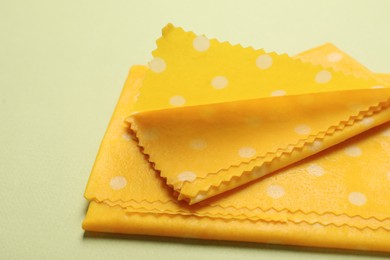 Photo of Beeswax food wraps on light green background, closeup