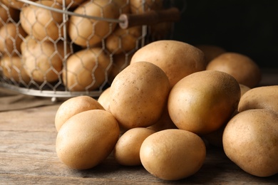 Photo of Raw fresh organic potatoes on wooden table, closeup