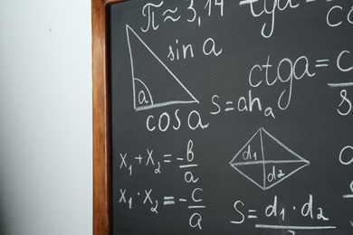 Photo of Chalkboard with many different math formulas on white wall, closeup