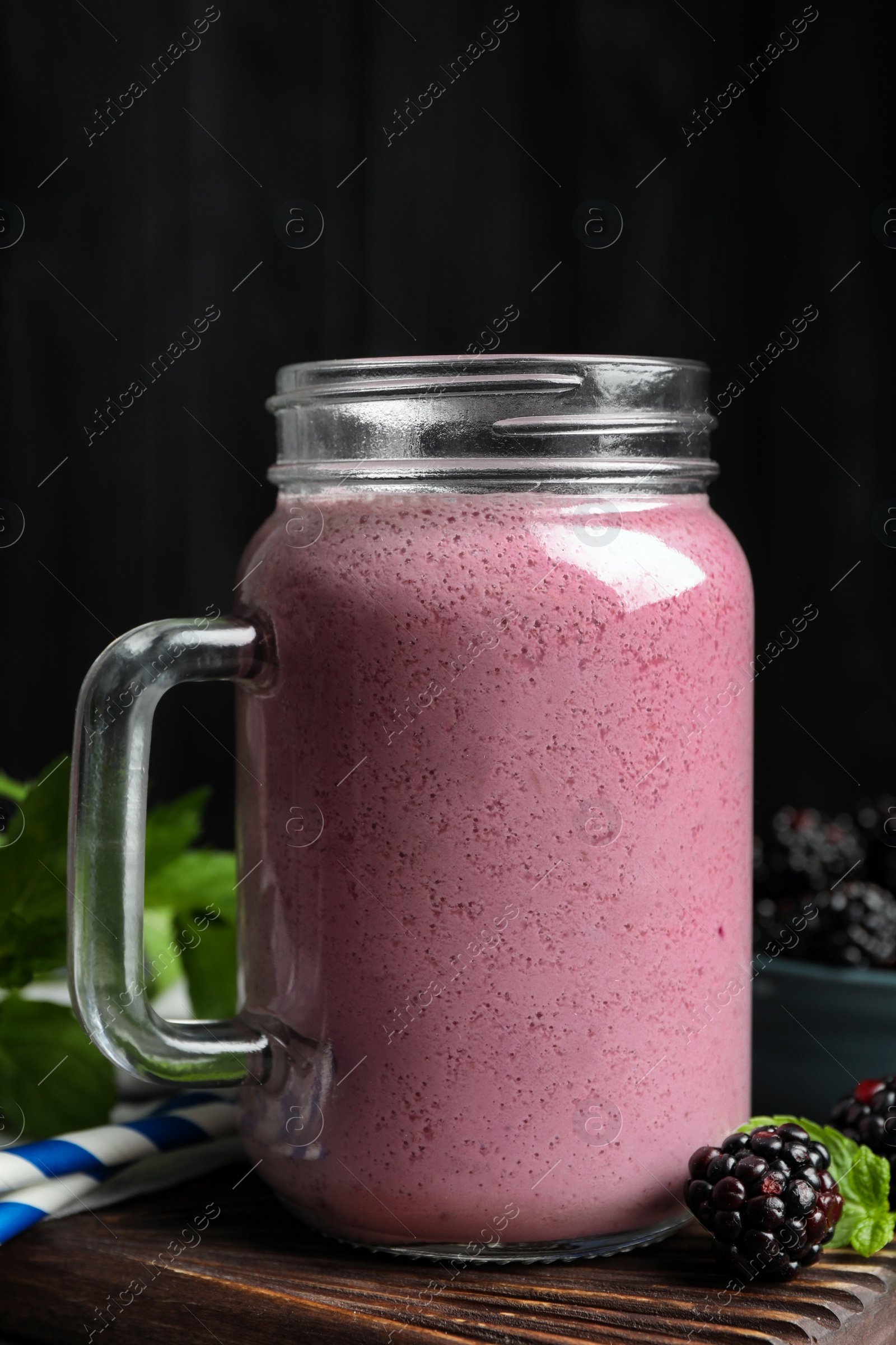 Photo of Mason jar of blackberry smoothie and berries on table