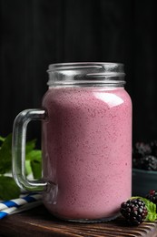 Mason jar of blackberry smoothie and berries on table