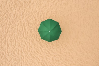 Image of Green beach umbrella on sandy coast, aerial view