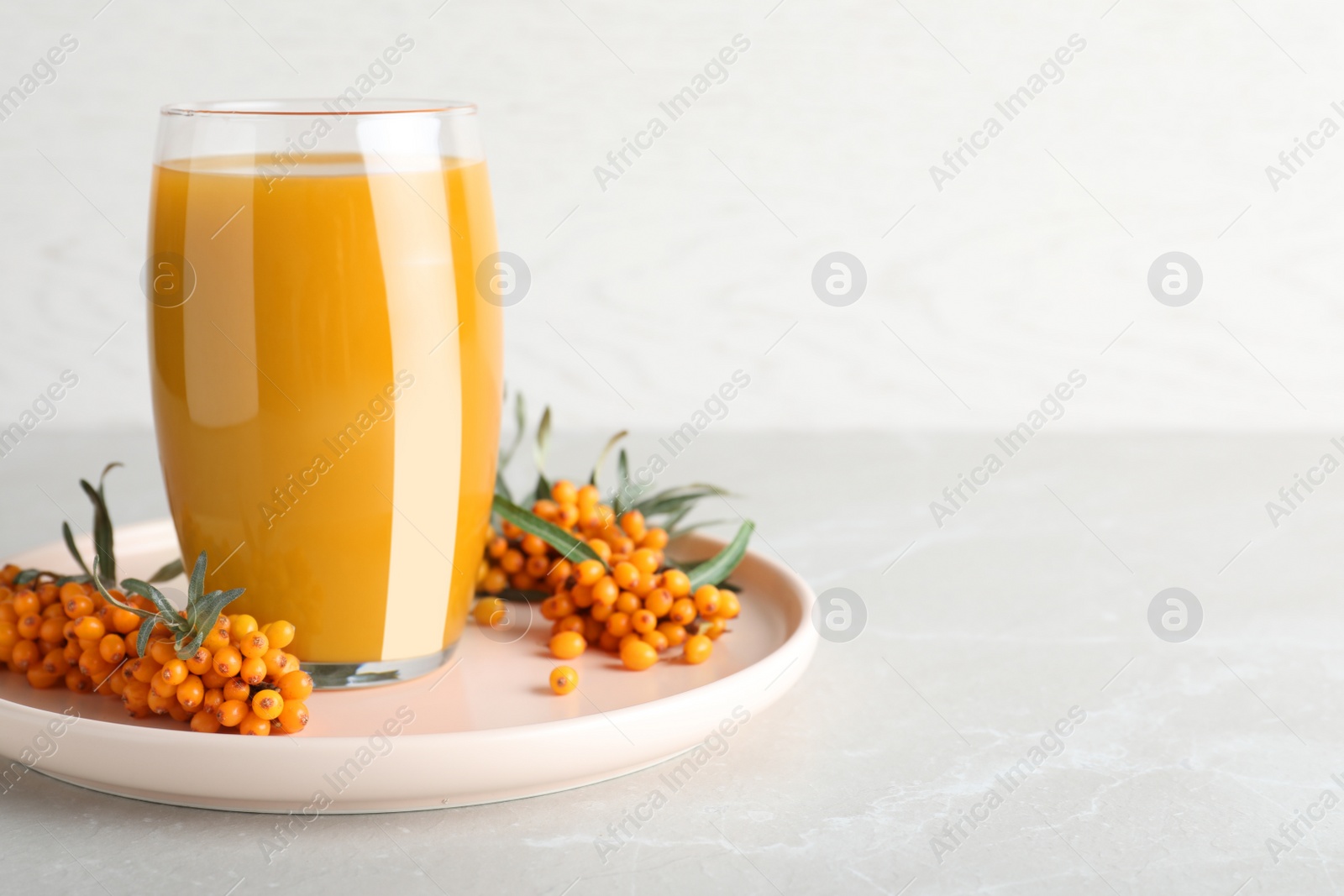 Photo of Delicious sea buckthorn juice and fresh berries on light grey marble table. Space for text
