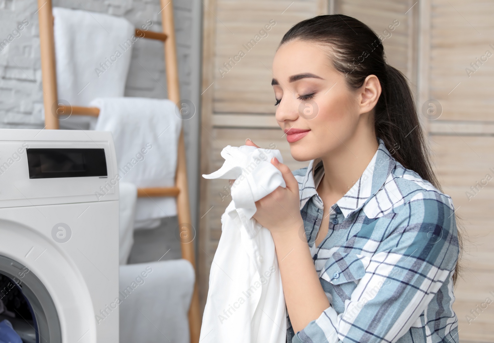 Photo of Young woman doing laundry at home