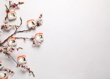 Photo of Flat lay composition of tasty sushi rolls with salmon and blossoming tree twigs on light table, space for text